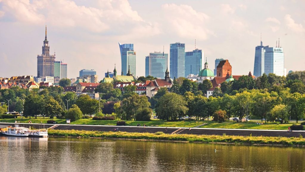 Panorama Warszawy z Wisłą, w tle nowoczesne drapacze chmur i historyczne budynki.