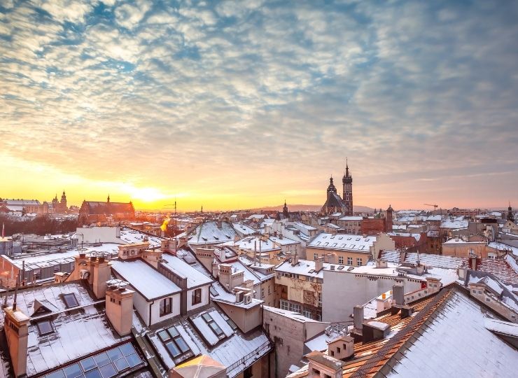 Winter aerial view of snow-covered city of Krakow in Poland -rooftops at sunrise with visible church towers.
